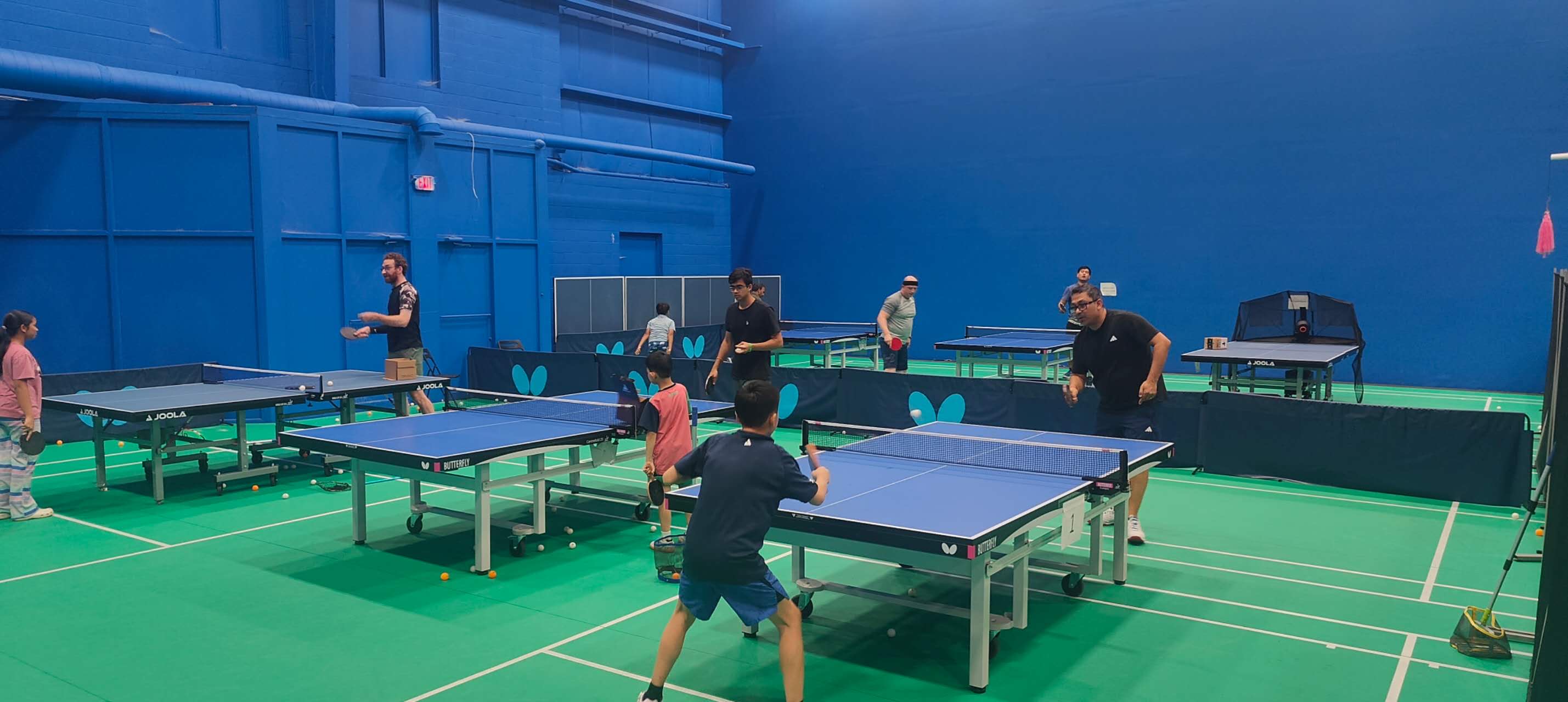 Youth and adult players enjoying table tennis at J&M Brothers — families playing together